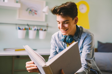 Wall Mural - Teenage boy reading book in his room.