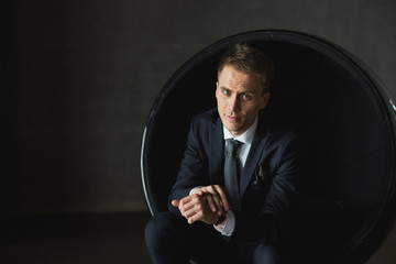 young businessman sitting in chair on grey background