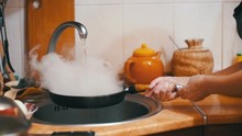 Wash Hot Frying Pan Turns A Jet Of Cold Water Into Steam In A Sink Of Home Kitchen. Slow Motion