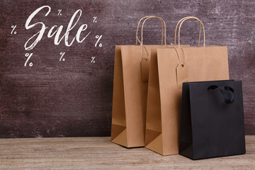 Wall Mural - Mockup of blank shopping bags. Sale discounts. Brown and black craft packages. Concept for sales or discounts. Recycled paper. Wooden rustic board.