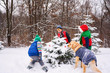 © RooM The Agency - Three children decorating a Christmas tree in the garden with their golden retriever dog