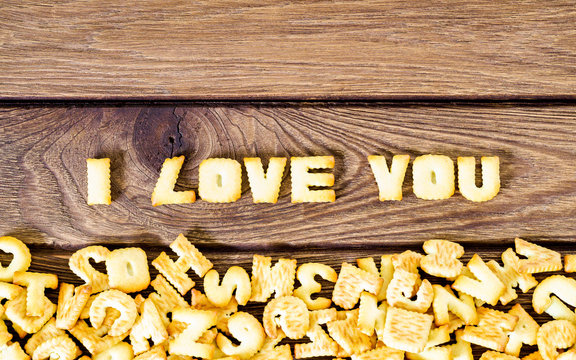 I love you. Text from the salty crackers as printed English letters that lie on a wooden background. Top view.