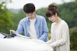 © amanaimages - Couple looking at a map in front of a car