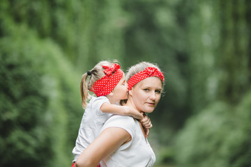 Wall Mural - Mother with red bow on her head holds little girl on her back