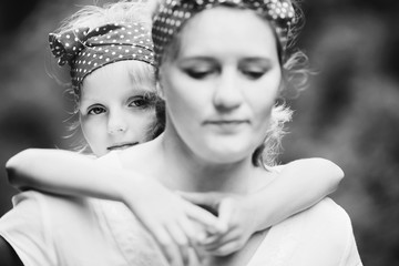 Wall Mural - Girl looks over mother's shoulder while she holds her on the back