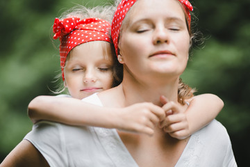 Wall Mural - Mother and daughter close their eyes holding each other tightly