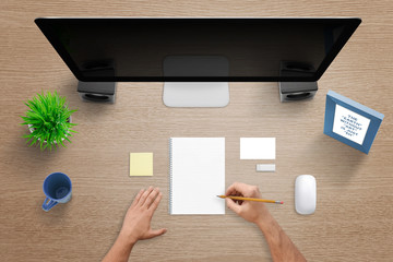 Poster - Top view of work desk with computer, pad, note, blank business card, mouse, plant, mug and desk frame. Man write on blank pad.