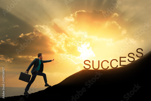 Silhouette Of Successful Businessman With Briefcase Walking To Top Of Mountain With Powerful Of Sunlight Sky Background Young Worker Reaching Goal Success And Achievement In His Life Copy Space Buy This