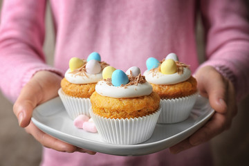 Wall Mural - Woman holding plate with delicious Easter cupcake