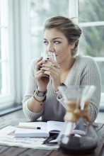 Portrait Of Young Woman With Glass Of Coffee Looking Through Window