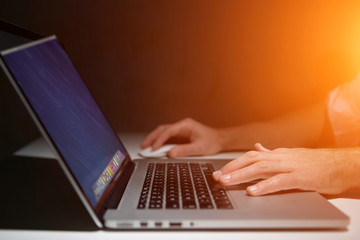 Hand typing on a keyboard of laptop with operating system screen on background