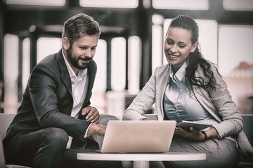Poster - Businesspeople sitting and discussing over laptop