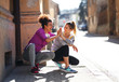 © BalanceFormCreative - Two young woman taking a break after jogging ,early in the morning.They crouching and laughing.