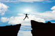 Man jump through the gap between hill.man jumping over cliff on sunset background,Business concept idea