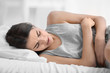 © Africa Studio - Young woman suffering from abdominal pain while lying on bed at home. Gynecology concept