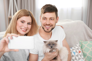 Canvas Print - Happy couple taking photo with cat at home