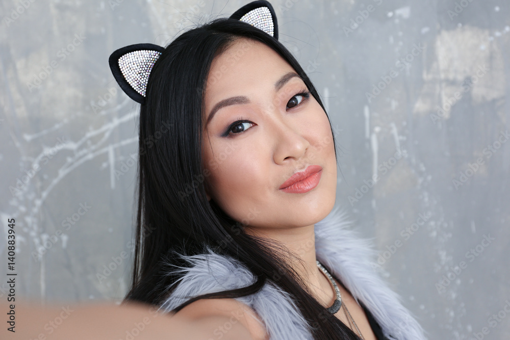 Young woman in cat ears on color background