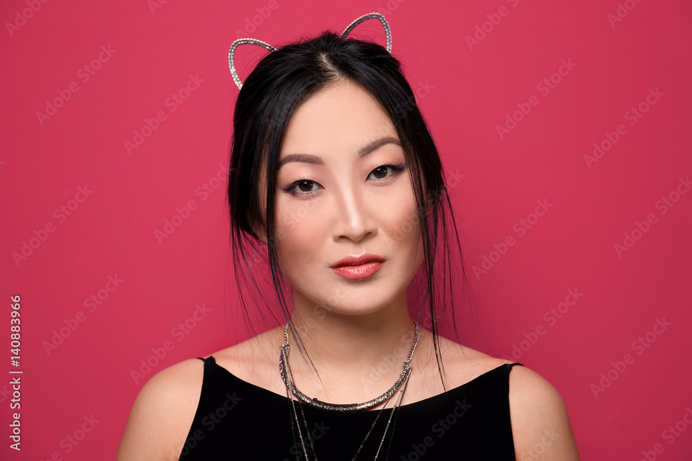 Young woman in cat ears on color background