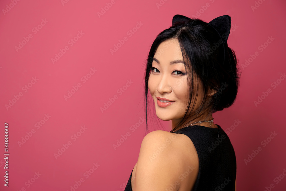Young woman in cat ears on color background
