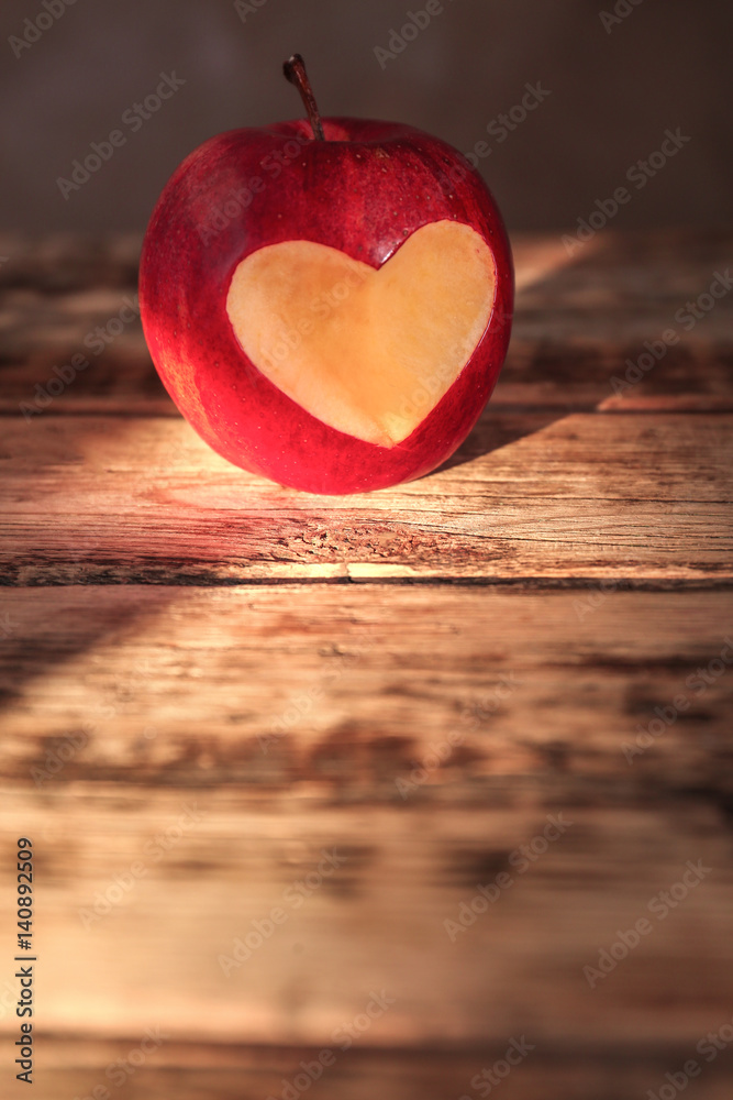 Fresh red apple with heart-shaped cut out  on wooden table