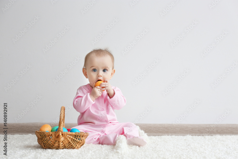 Cute funny baby with basket full of Easter eggs at home