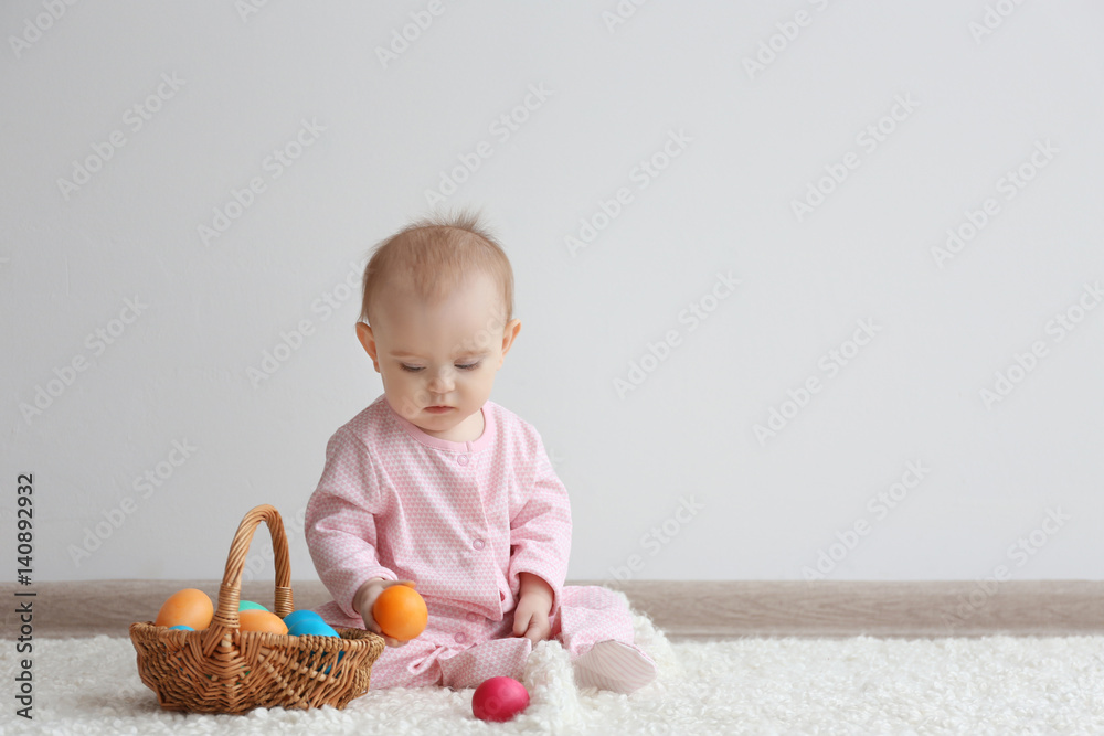 Cute funny baby with basket full of Easter eggs at home