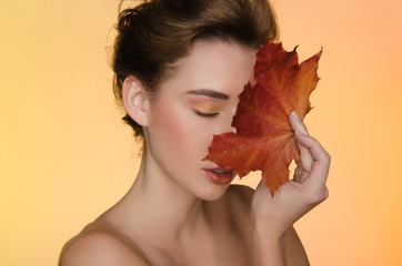 woman with maple autumn leaves on yellow background