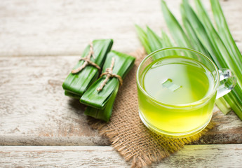 Wall Mural - Glass of pandan juice and pandan leaves on wood background