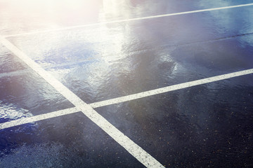 Empty parking lot with stripes . Wet concrete with reflection of blue sky with clouds