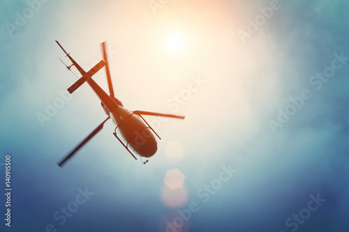 Fotografía Helicopter flying in the blue sky with sun