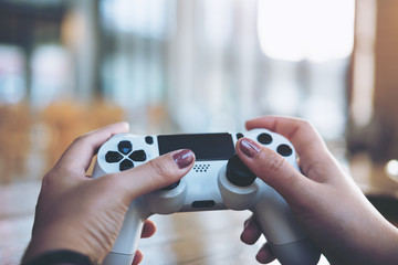 Woman's hands holding the game controller and playing games in a house