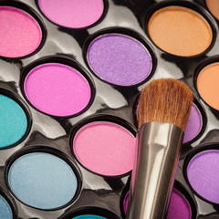 Macro of makeup brush with colorful eyeshadow palette