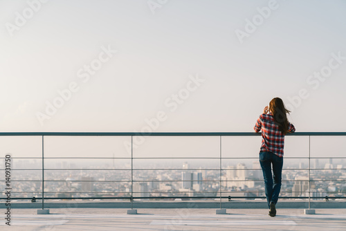 Cuadros en Lienzo Woman using mobile phone at rooftop during sunset with copy space, communication