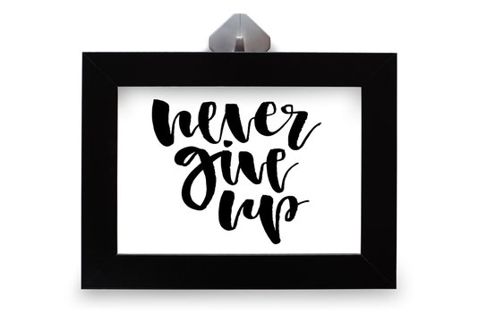 Never give up. Inspirational quote, handwritten text. Modern calligraphy. Black wooden frame. Close-up