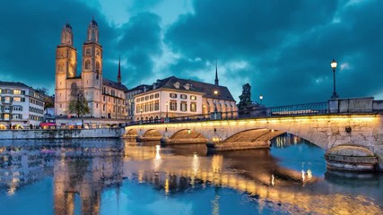 Fototapete - Munsterbrucke and Grossmunster church reflecting in river Limmat, Zurich, Switzerland (static image with animated sky)
