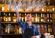 Barman at work in pub,Portrait of cheerful barman worker standing,Waiter giving menus,A pub.Bar.Restaurant.Classic.Evening.European restaurant.European bar.American restaurant.American bar.