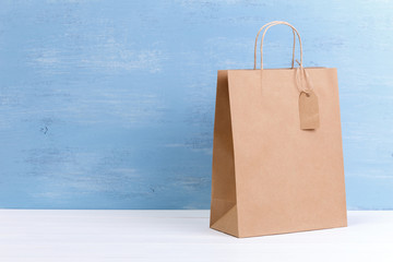 Mockup of blank shopping bag. Brown craft package. Concept for sales or discounts. Recycled paper. Blue wooden rustic board.