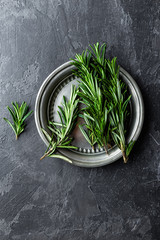 Wall Mural - Fresh rosemary twigs on dark culinary background, top view, flat lay, copy space