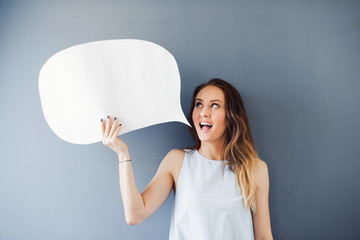 Young woman posing with a speech bubble against a gray background 