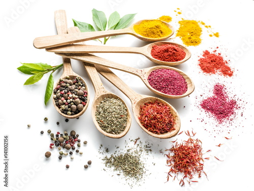 Fotografía Assortment of colorful spices in the wooden spoons on the white background