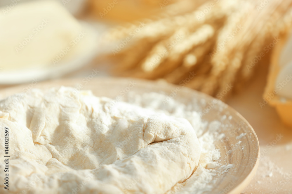 Plate with raw dough on kitchen table, closeup