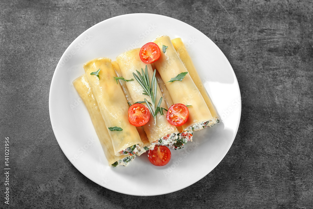 Delicious stuffed cannelloni with cherry tomatoes on plate