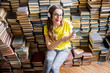 © rh2010 - Young woman student listening to the music sitting on the heap of books at the old library