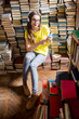 © rh2010 - Young woman student listening to the music sitting on the heap of books at the old library