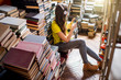 © rh2010 - Young woman student listening to the music sitting on the heap of books at the old library