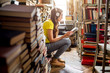 © rh2010 - Young woman student listening to the music sitting on the heap of books at the old library