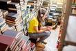 © rh2010 - Young woman student listening to the music sitting on the heap of books at the old library