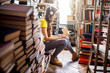 © rh2010 - Young woman student listening to the music sitting on the heap of books at the old library
