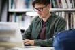 © ReeldealHD images - Student working on laptop in library