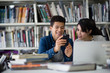 © ReeldealHD images - Students looking at smartphone in library